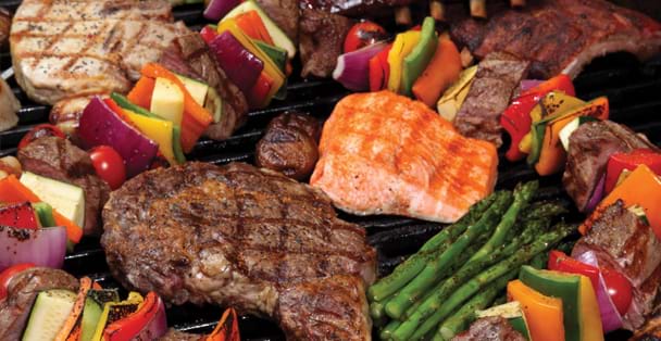 A variety of barbecued meat and vegetables on a gr
