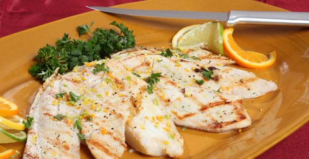 A plate of grilled tilapia on a plate with the car