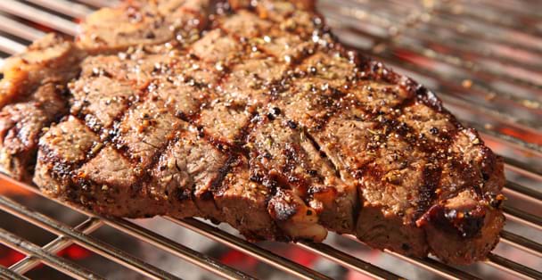 Close up of a t-bone steak on a grill.